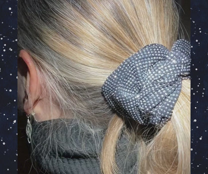 Closeup of model wearing silver-white rhinestone scrunchie, night scene with stars.