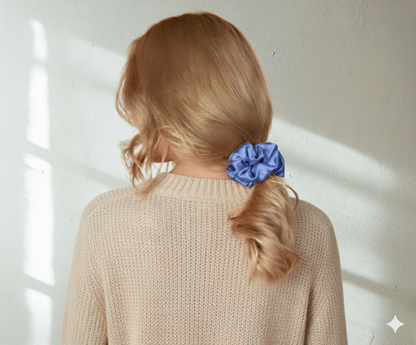 Person with pacific blue colored silk scrunchie in their hair against a light background