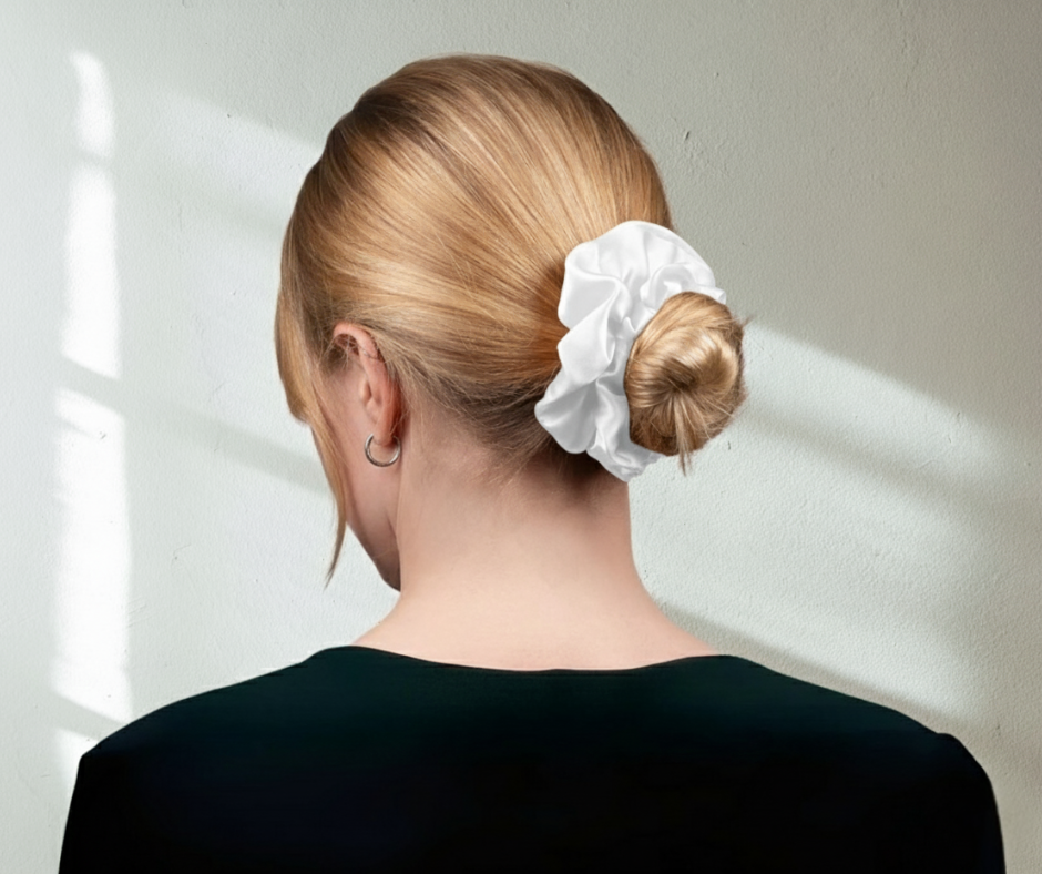 Model with a white silk scrunchie in their hair against a neutral background