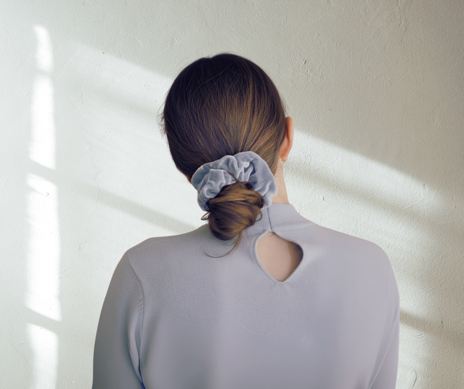 Model with a ice blue silk velvet scrunchie in their hair against a light background